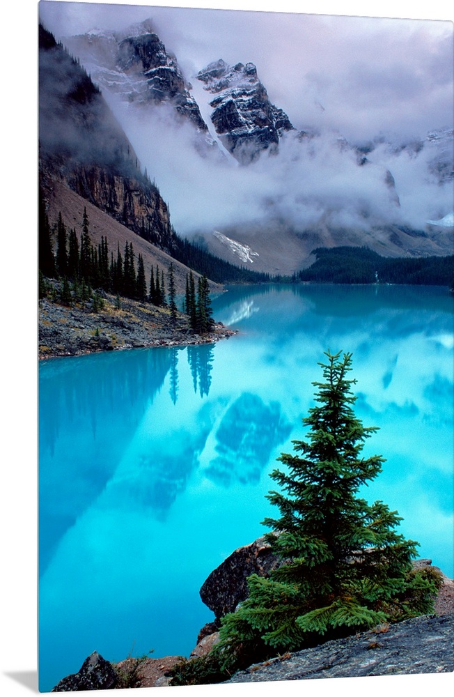 From the National Geographic Collection a photograph of mountains reflecting in water as clouds pass between them; in the ...