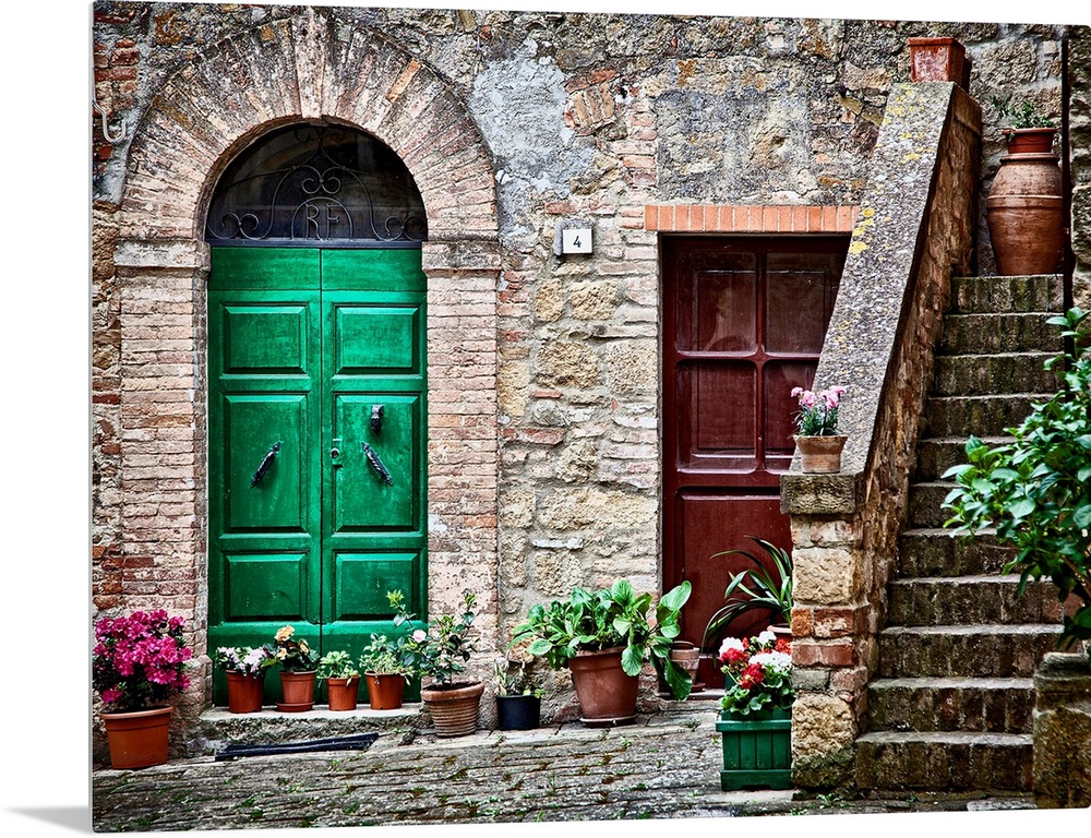 A rustic city street and ancient home built from stone and brick with brightly painted doorways lined with plants in terra...