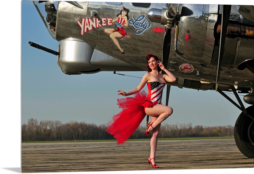Beautiful 1940's style pin-up girl standing in front of a B-17 bomber.
