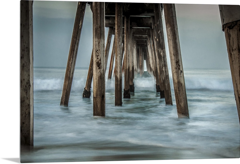 View from below of a wooden pier stretching out into the ocean.