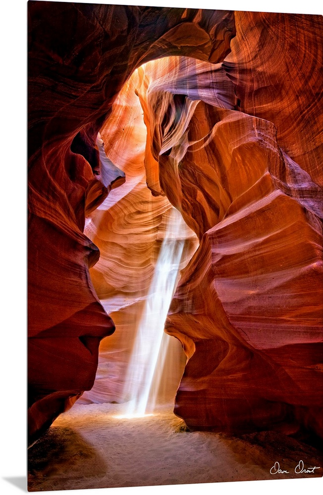 Photograph of the sun shining through the canyon top onto the sand in Antelope Canyon.