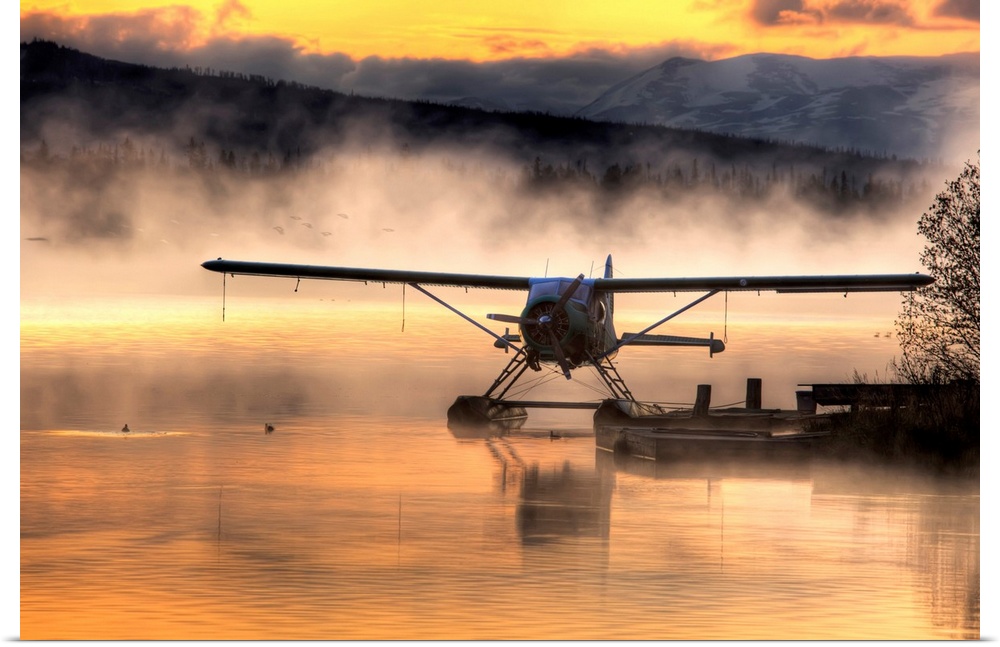 Giant photograph displays a seaplane sitting next to a dock as a soft fog rolls over the water.  In the background, the fa...