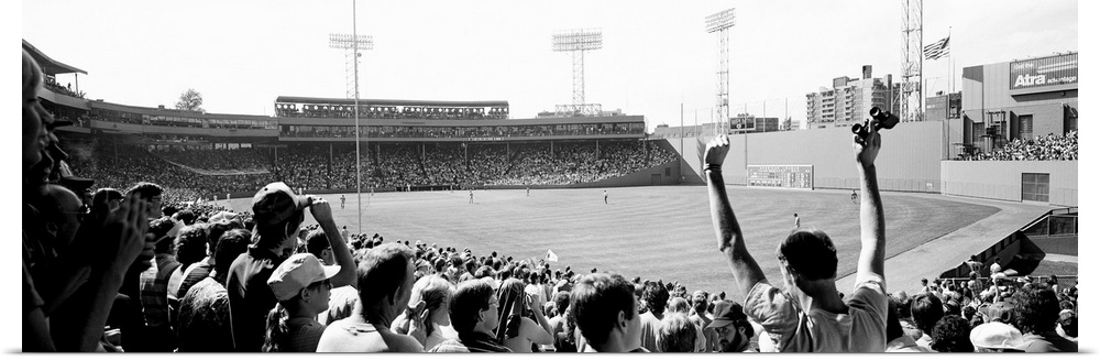 Big, panoramic black and white photograph of Fenway Park in Boston, with fans standing and cheering in the foreground.