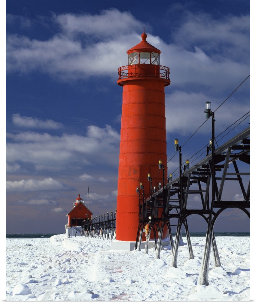 A lighthouse in Michigan is photographed closely as snow covers the ground surrounding it.