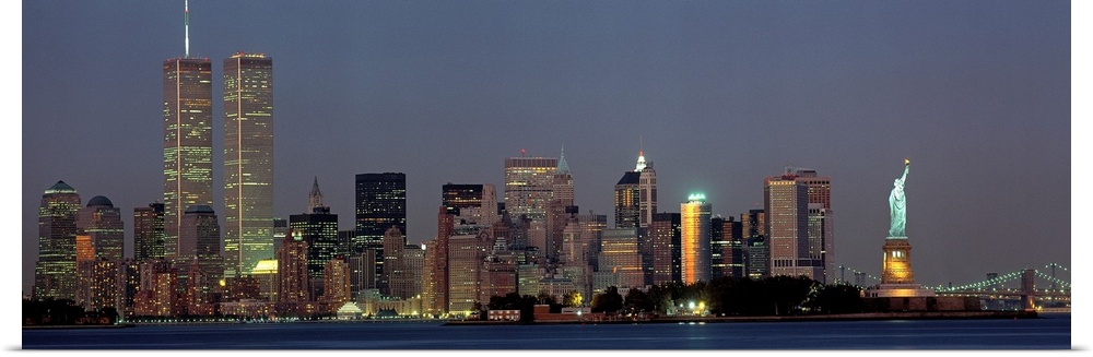 Panoramic photograph of the New York skyline at night, with the Twin Towers and the Statue of Liberty on a large wall hang...
