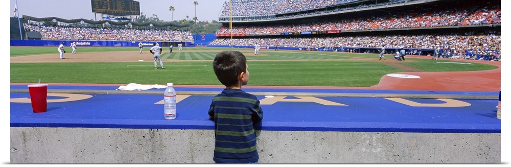 This decorative all wart is a panoramic photograph of a child watching a baseball game from a dug out.