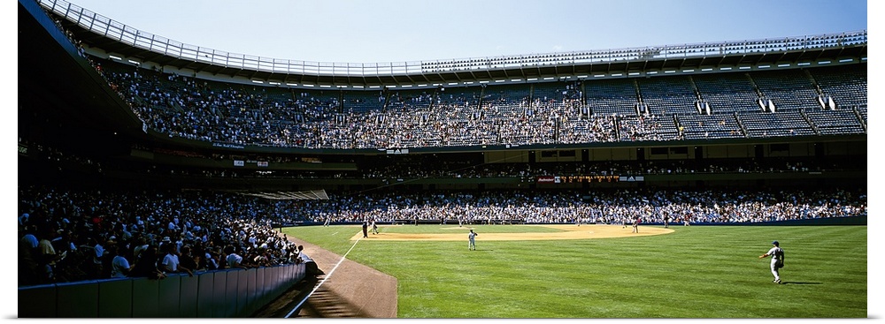 Wide angle photograph of Yankee Stadium with stands full of fans, during a baseball game in New York City.
