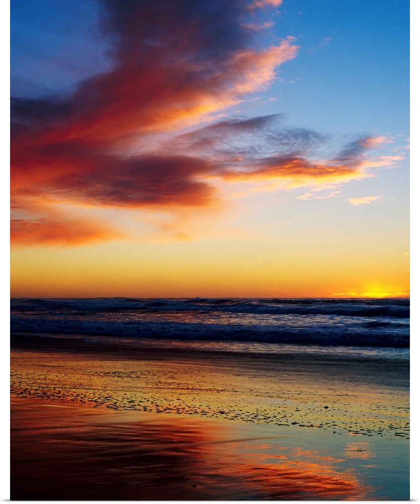 Photograph of a cloudy beach sunset with gently rolling waves in the distant