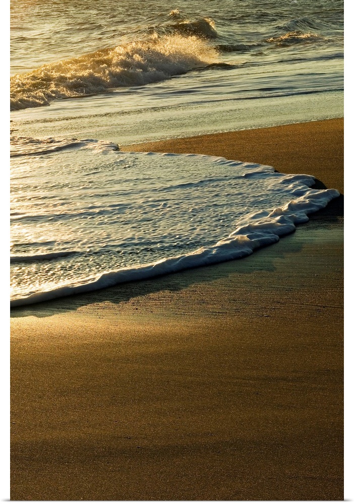 A vertical photograph of waves washing up on the shore in the morning.