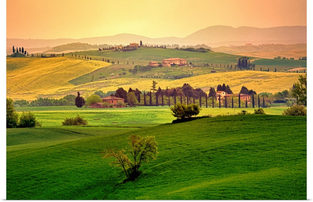 Photograph of hillsides with mountain silhouettes in the background.  The hills are covered with homes, trees, bushes, and...