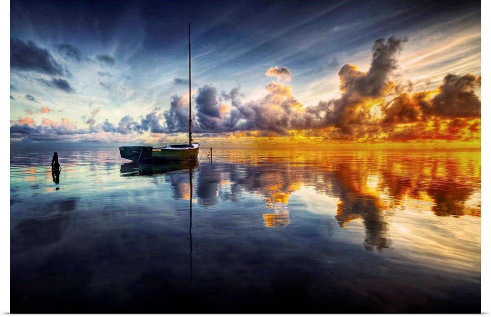 Dramatic clouds of sunset hanging over a reflective waterscape with a sailboat sitting in the foreground.