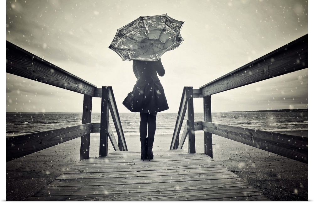 Black and white portrait of a woman standing on a wooden pier with a broken umbrella.