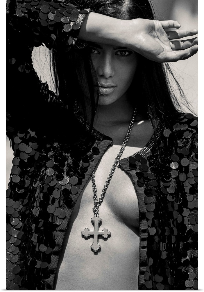 Black and white portrait of a nude woman wearing a black sequin jacket and a cross necklace.