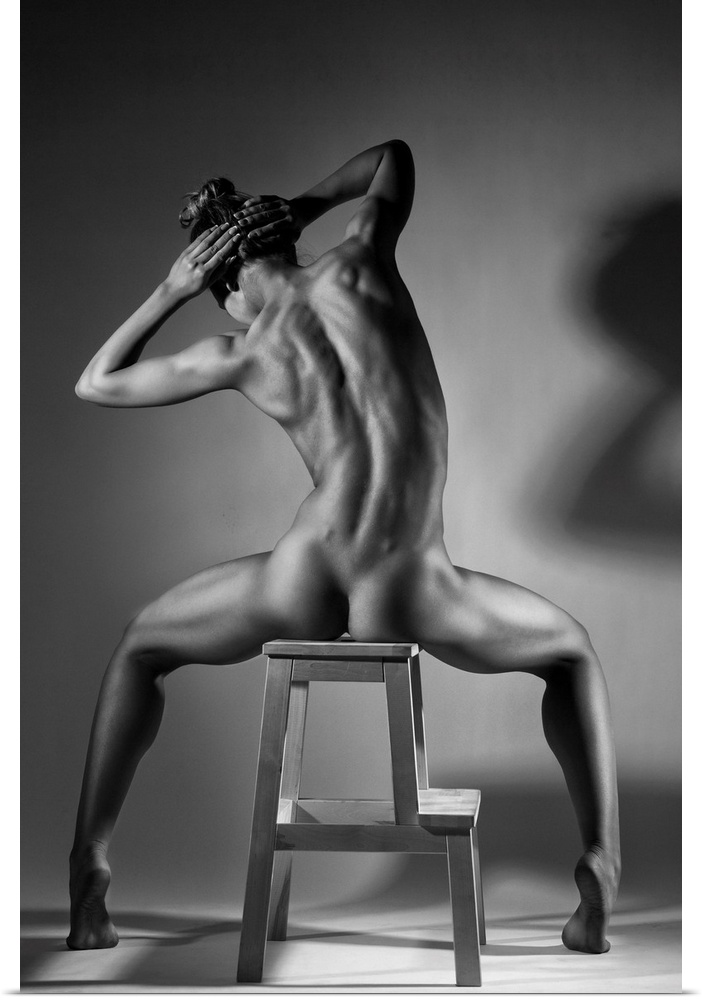 Black and white fine art photograph of a woman with her back to us, sitting in a chair and creating angles with her body.