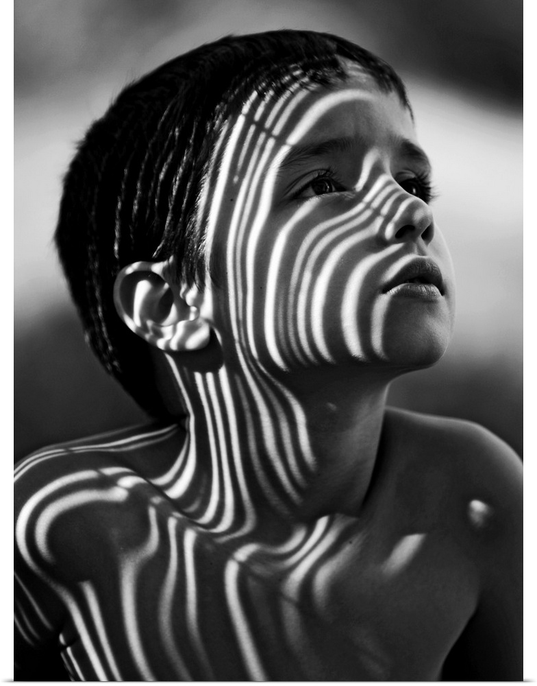 Portrait of a young boy with striped shadows across his face.