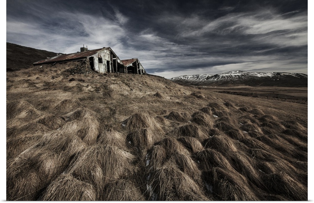 An abandoned farmhouse in Iceland, with mountains in the distance.