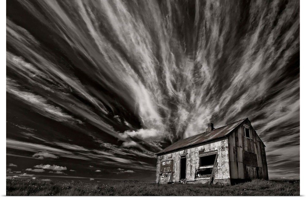 High contrast photo of a cabin in Iceland with clouds streaking overhead.