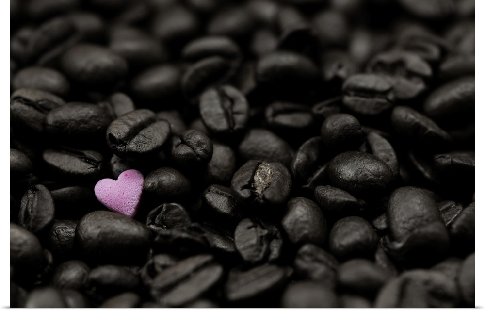 Close-up photograph of dark coffee beans and a single pink heart.