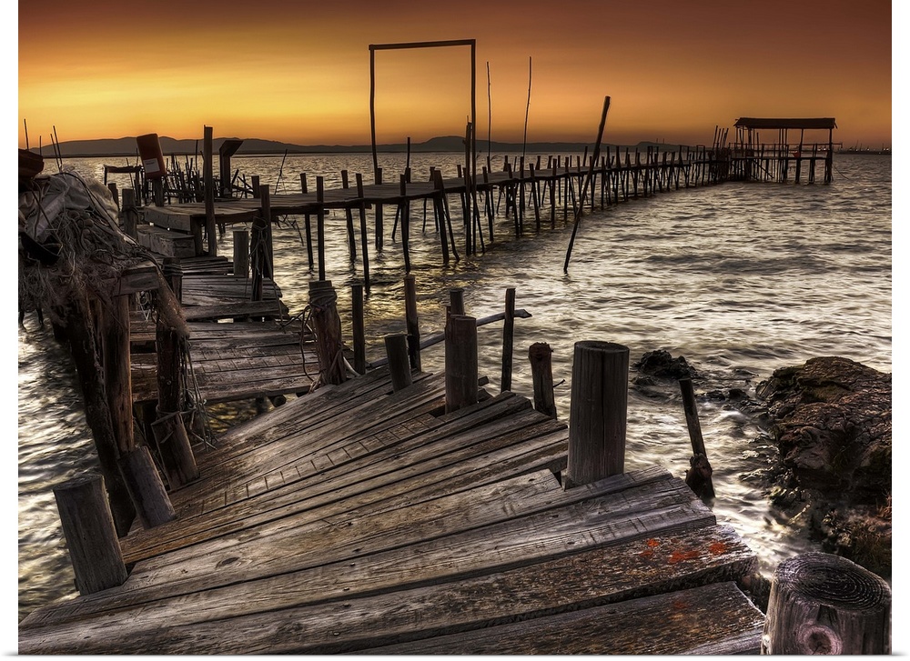 A decaying wooden pier in Carrasqueira, Spain, at sunset.
