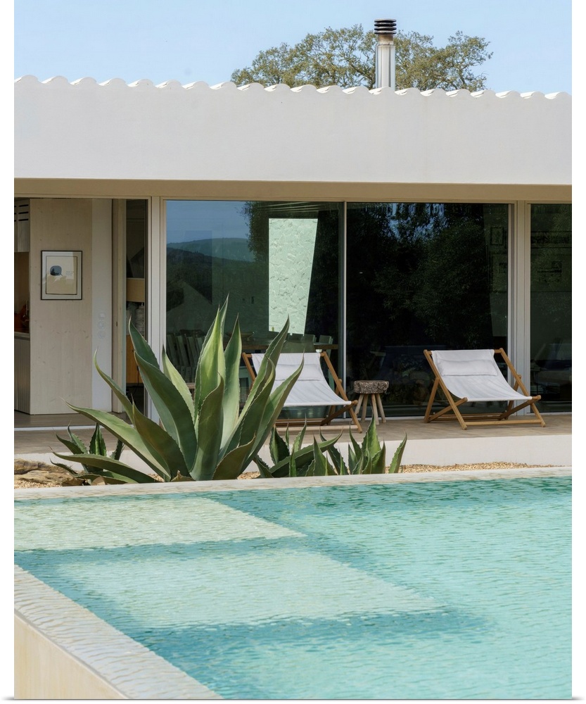 A cool-toned photograph of an outdoor mediterranean swimming pool and villa