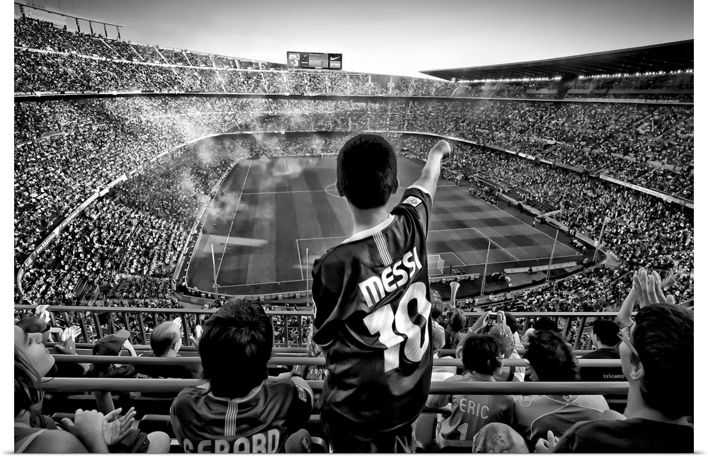 A black and white photograph of a child standing up among thousands of seated people in a sports stadium.