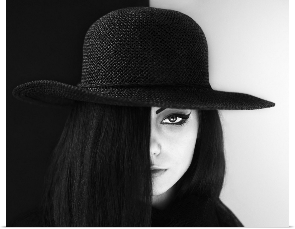 Portrait of a woman with face half obscured, wearing a large hat.