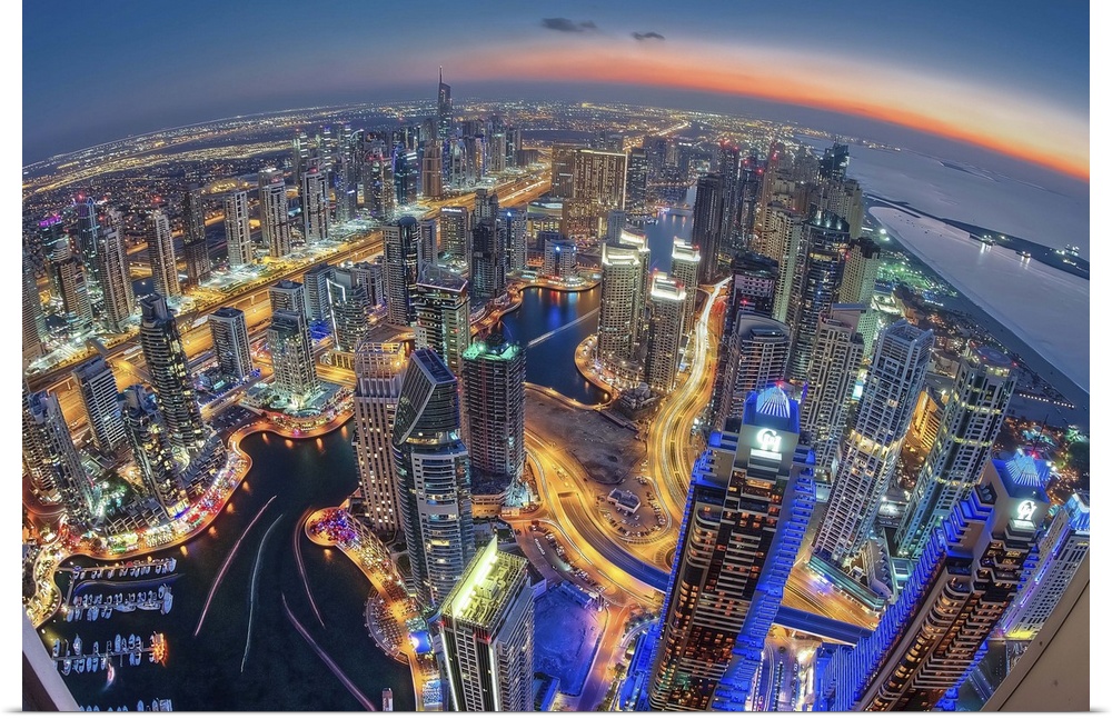 The city of Dubai illuminated with brilliant rainbow lights in the early evening. The curvature of the Earth is visible fr...