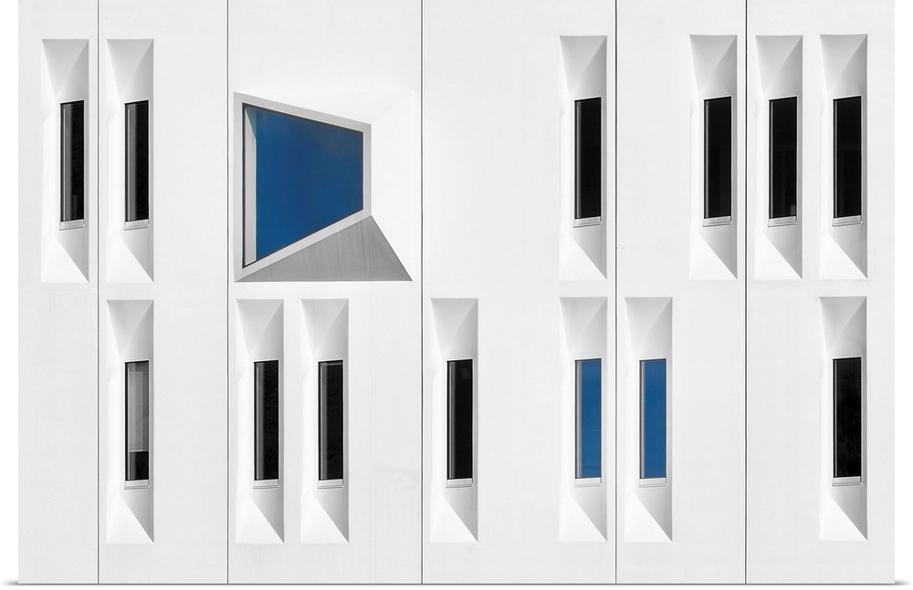 Facade of a white building with narrow windows reflecting black and blue.