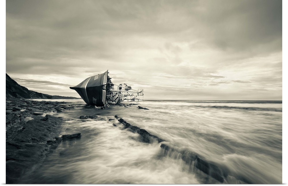A beached boat laying on its side on the shore.