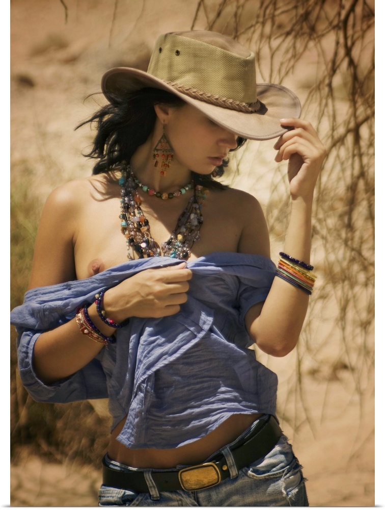 A model with a cowboy hat and beaded jewelry walking in the desert.