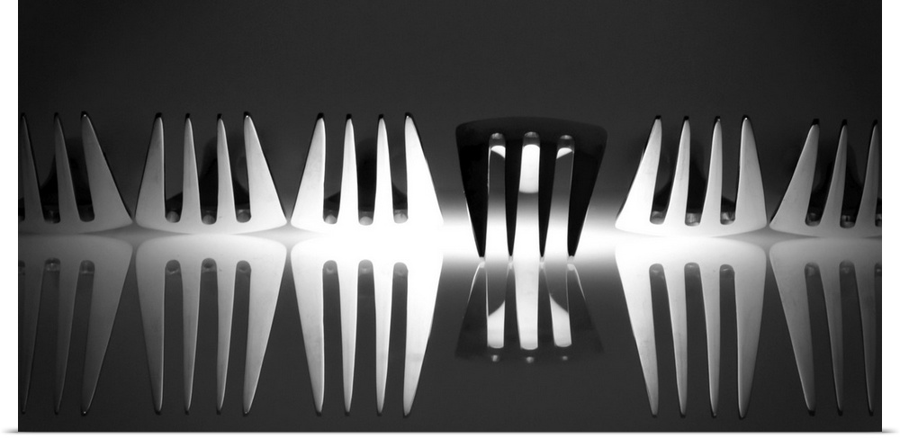 Abstract image of a row of forks with light reflecting from below with one turned upside down.