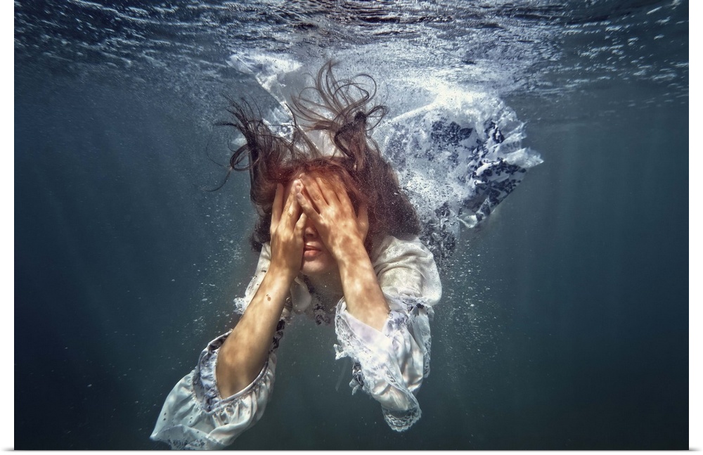 A woman underwater in a white dress with her hands over her eyes.