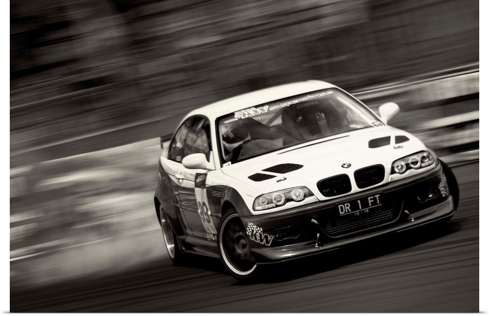A black and white photograph of a sports car drifting against a blurred background.
