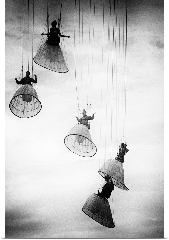 Performers hanging from wires in the air, wearing hoop skirts.