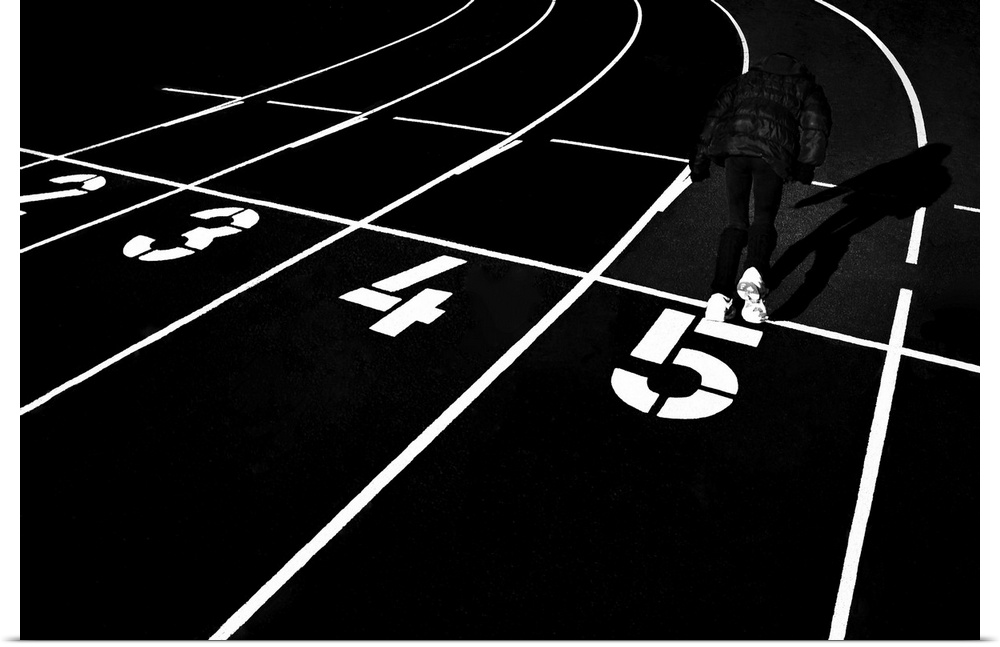 A man running in the number 5 lane on a track in a stadium, in high contrast black and white.