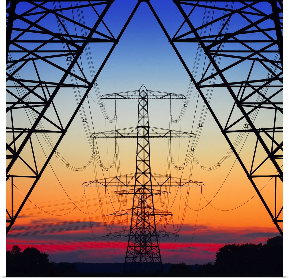 Looking the center of electrical pylons silhouetted in the setting sun behind them.
