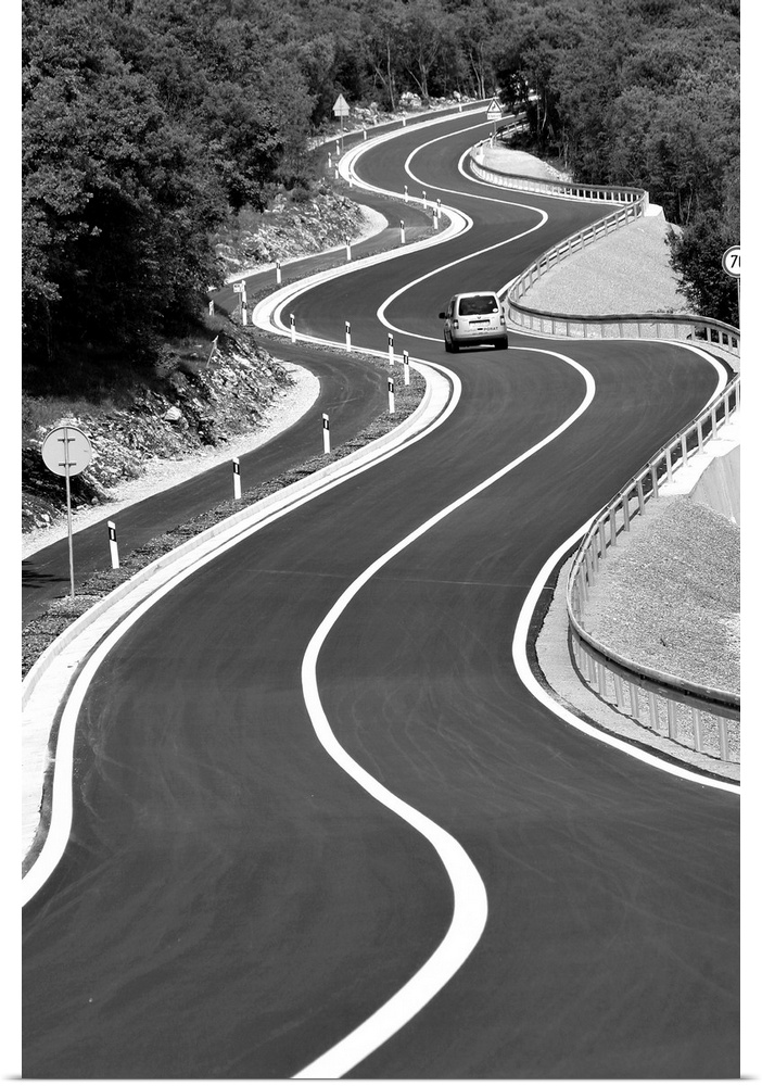A car traveling down a stretch of very curvy road.