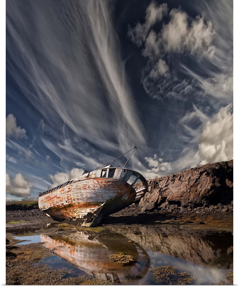 An abandoned and decaying ship beached on land under dramatic clouds in the sky.