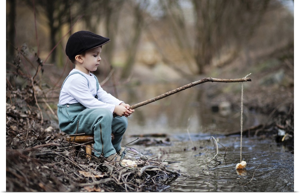 Portrait of a young boy at the edge of a stream with a simple fishing rod.