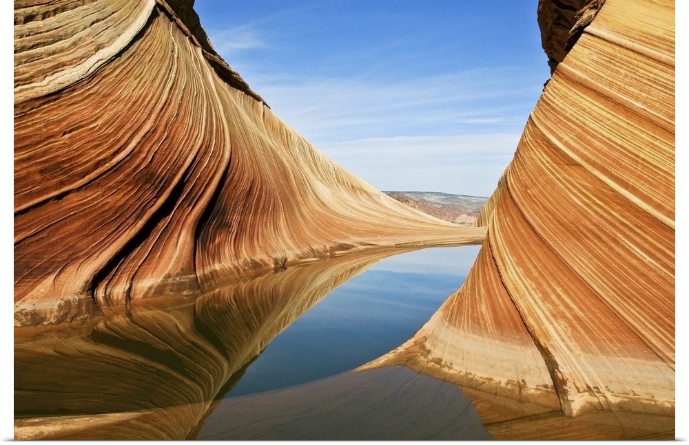 Striated rock formations in Vermilion Cliffs National Monument, reflected in the water of a stream.