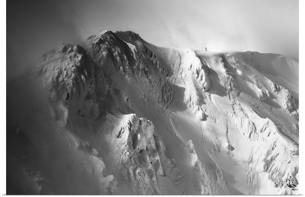 Black and white image of the Tatras Mountains with an immense amount of snow, with a tiny figure visible at the top, Slova...