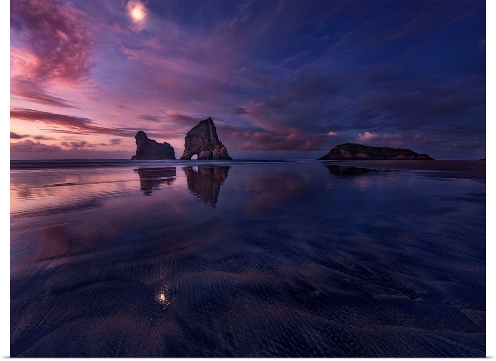 Low tide with large sea stacks and a colorful sky at dusk, Golden Bay, New Zealand.