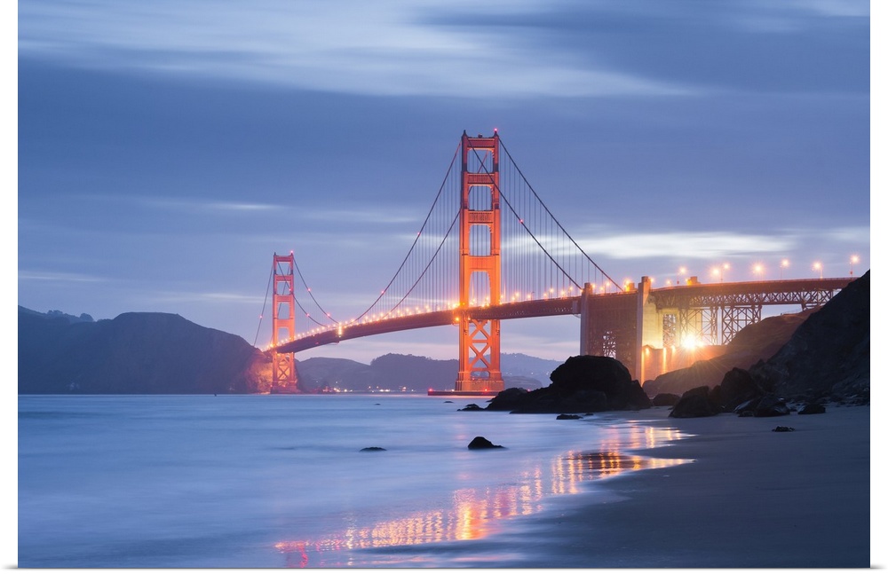 A soft and dreamy photograph of the golden gate bridge in San Francisco lit up in the early evening
