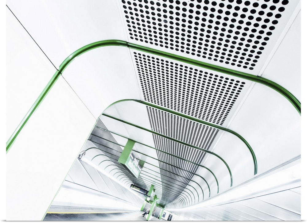 Abstract view of a stark white tunnel in a train station lined with bright green lines.