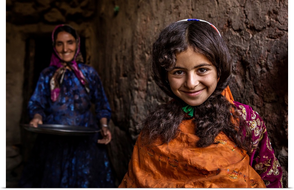 A smiling young girl with her mother standing behind her, Iran.