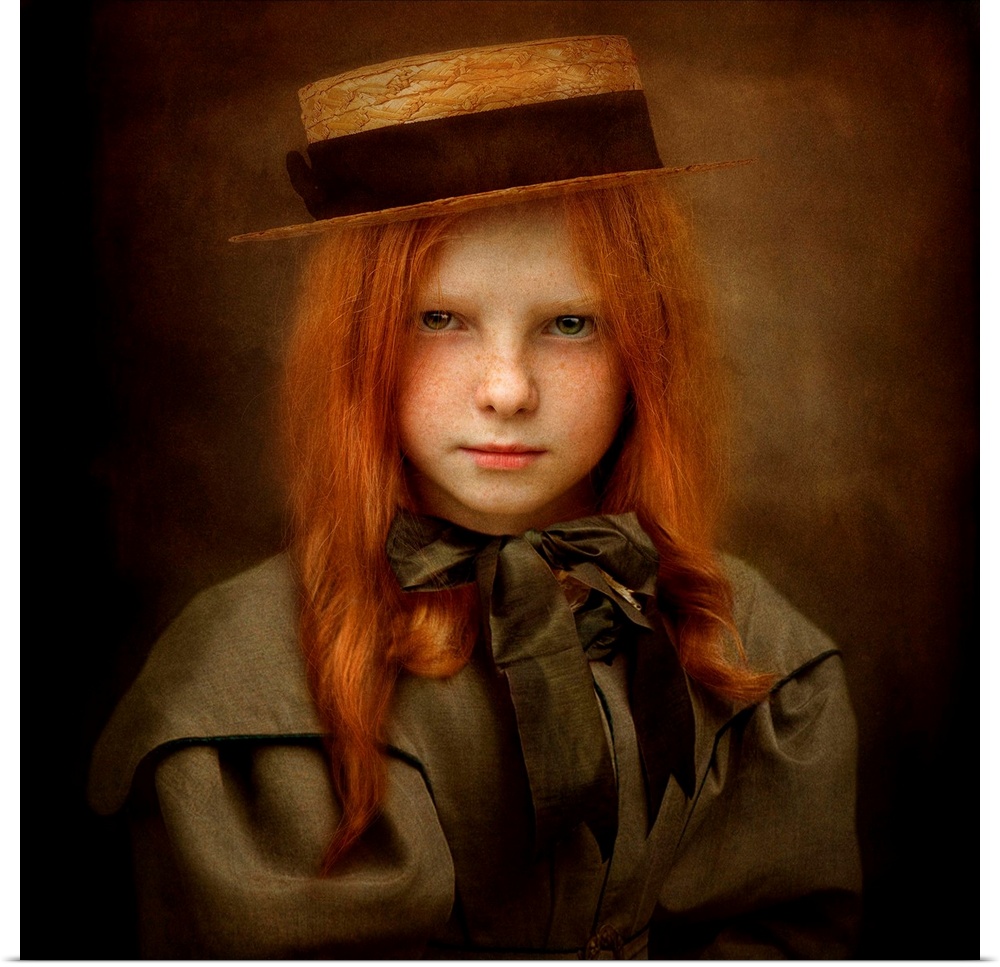 A child with long red hair wearing a straw hat and a ribbon tied in a bow.