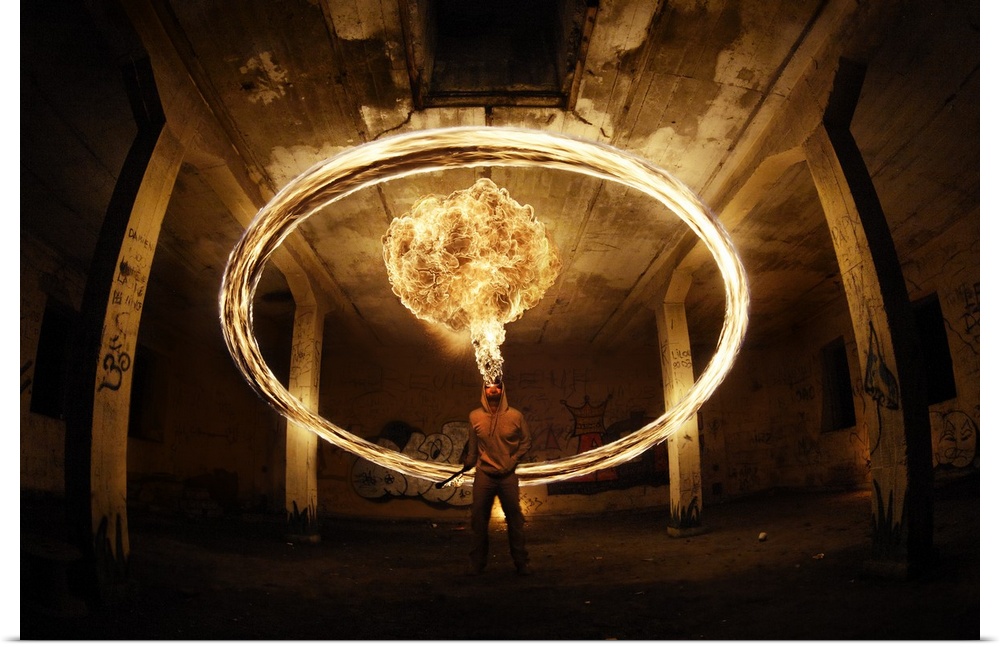 A man appears to breathe fire wit ha ring of light in the air around him, in a concrete structure.
