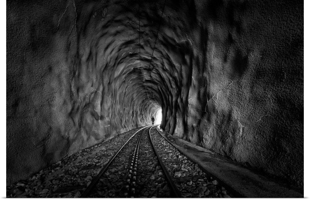 A figure walks along tracks toward the end of a tunnel.