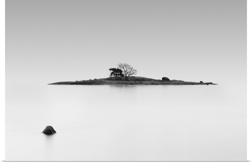 Black and white photo of a small island in the middle of still water, Finland.