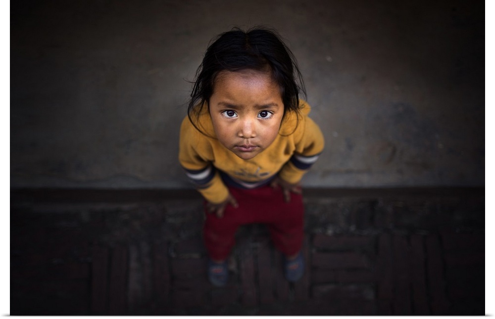 A young Nepalese girl looking up with large dark eyes.